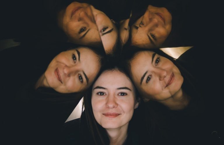 Eine Frau mit vier Spiegelbildern lächelt in einer kreativen Anordnung.