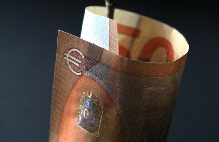 Eine teilweise aufgewickelte 50-Euro-Banknote auf dunklem Hintergrund.