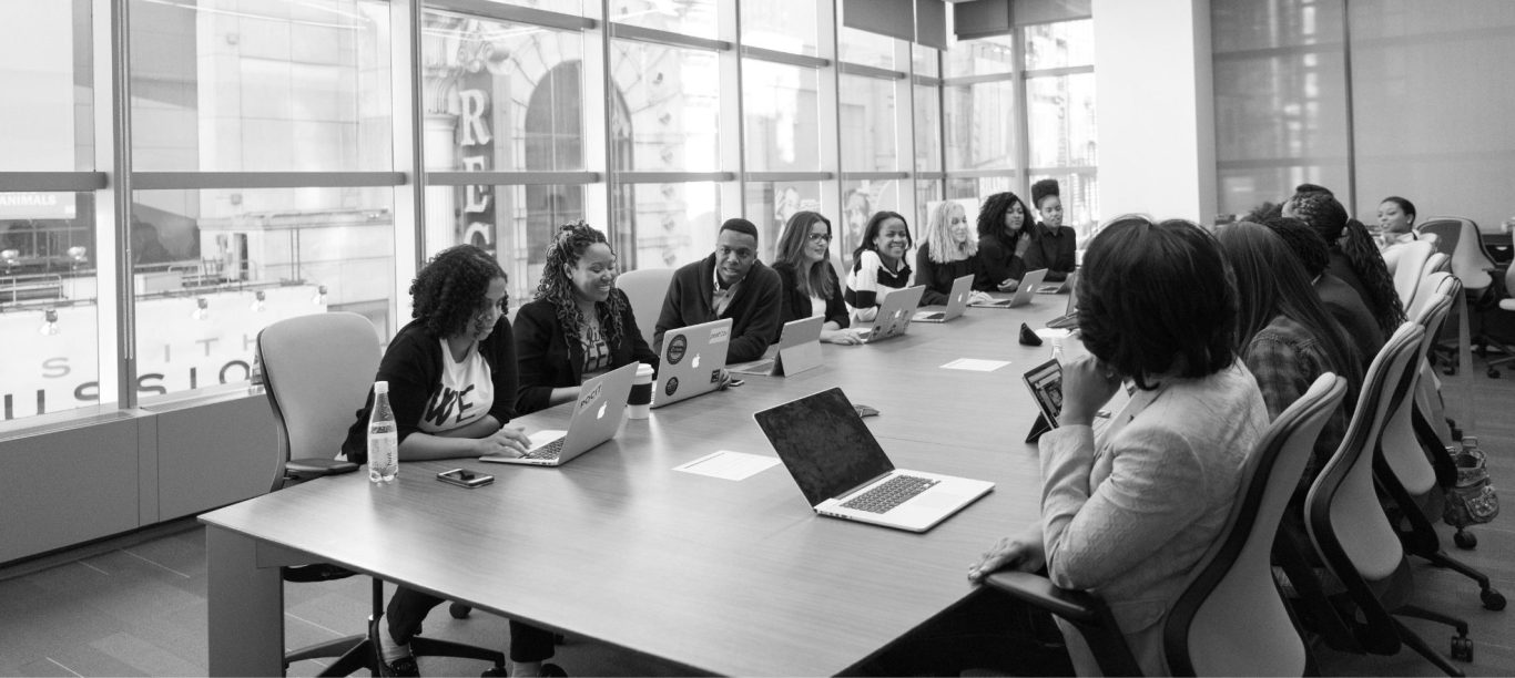 Geschäftstreffen mit mehreren Personen an einem langen Tisch in einem modernen Konferenzraum.