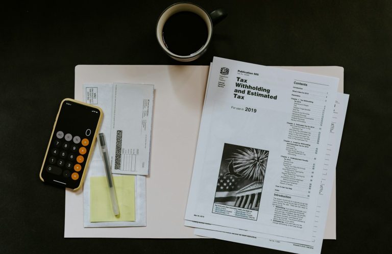 Schreibtisch mit Dokumenten, Stift, Taschenrechner und einer Tasse Kaffee.