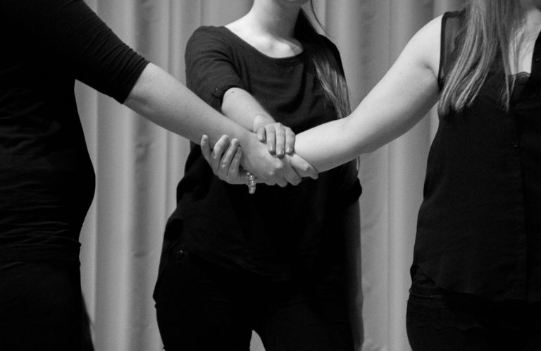 Drei Hände, die sich überlappend berühren, in Schwarz-Weiß.